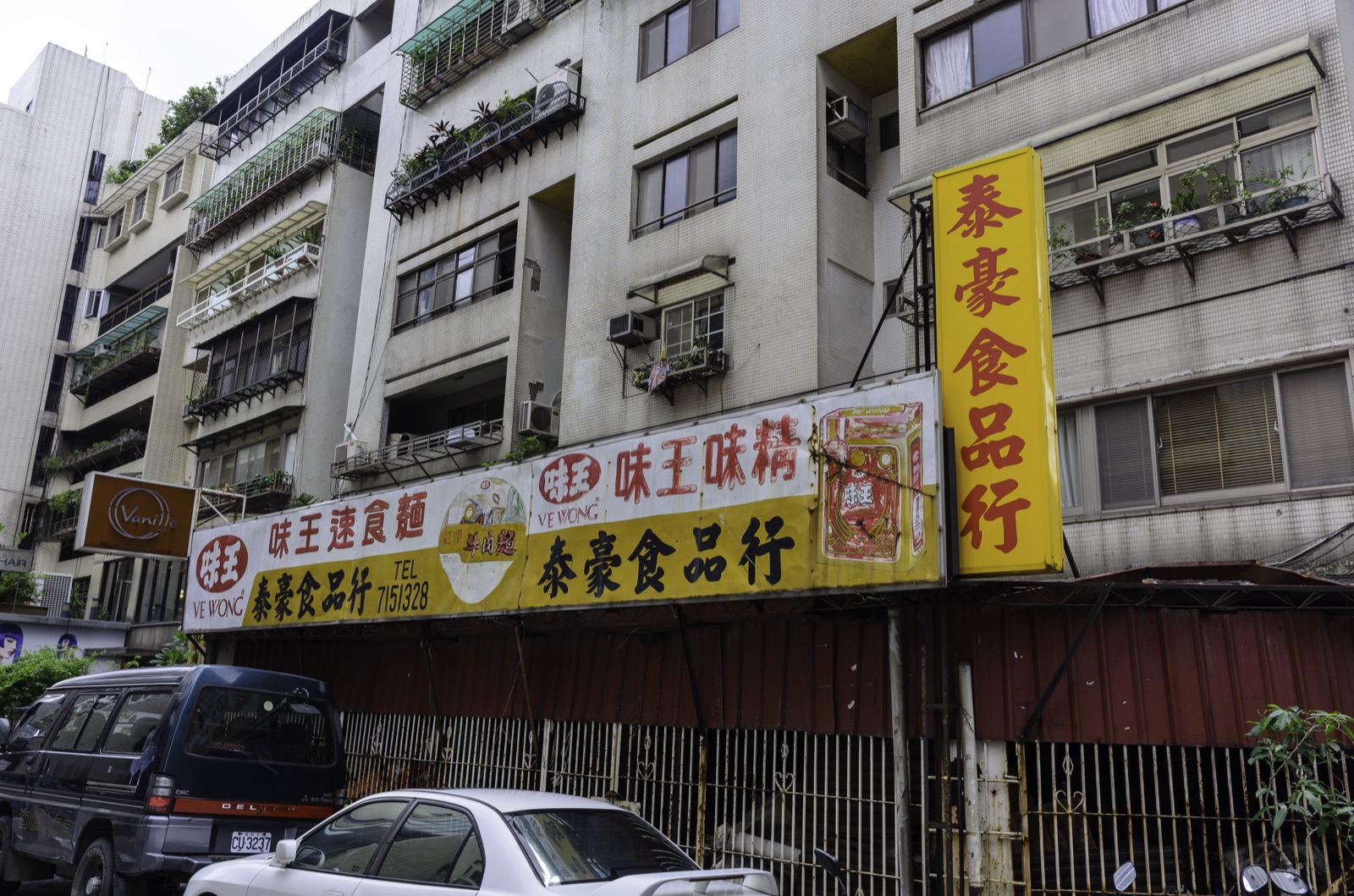 A hand-painted Ve Wong MSG and instant-noodle banner over a grocery wholesaler on Minquan East Road, Taipei, photographed in September 2015