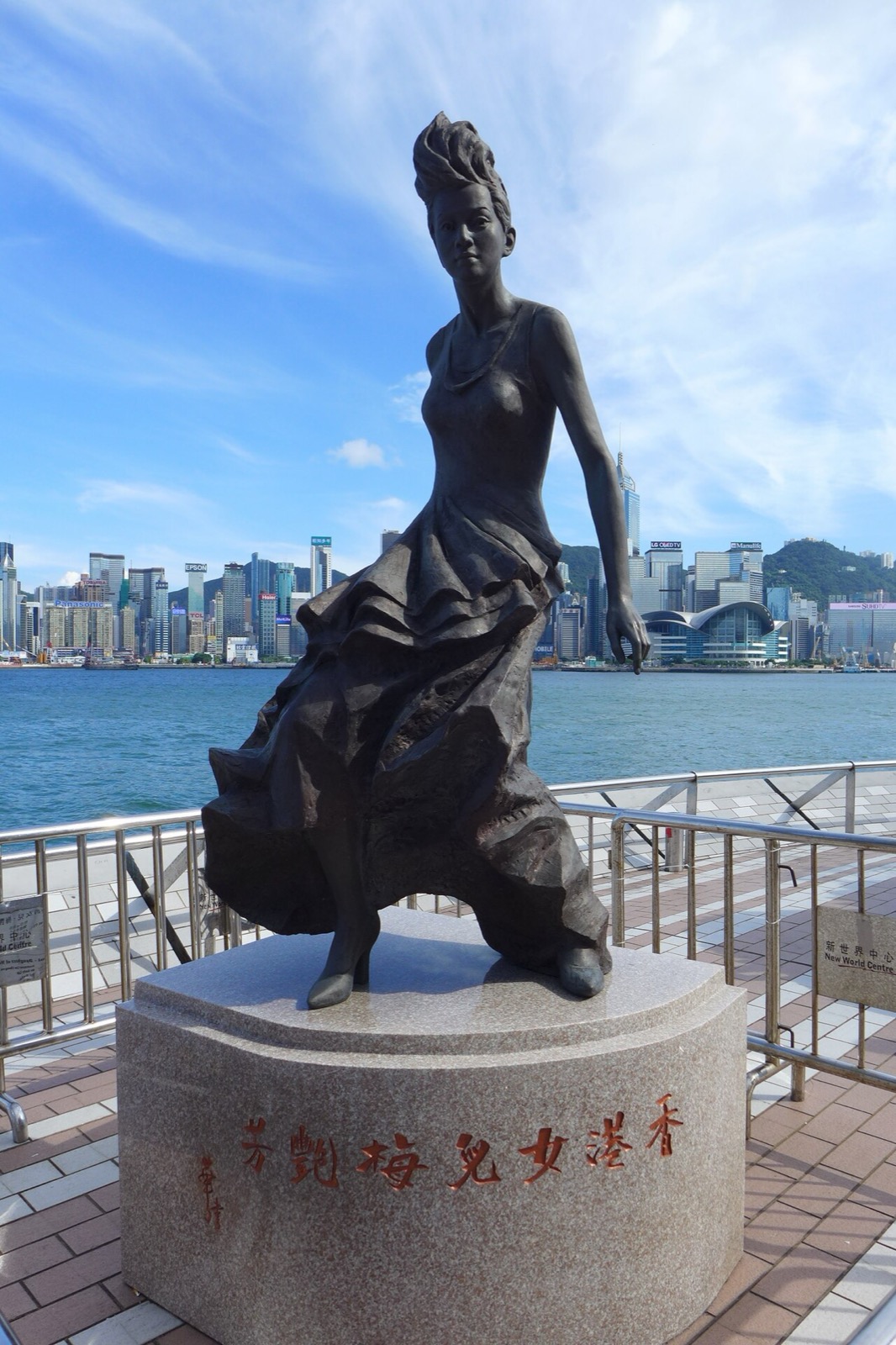 The bronze statue of Anita Mui on the Avenue of Stars, Tsim Sha Tsui, inscribed 香港女兒梅艷芳 — Hong Kong's Daughter, Anita Mui — with Victoria Harbour and the Hong Kong Island skyline behind