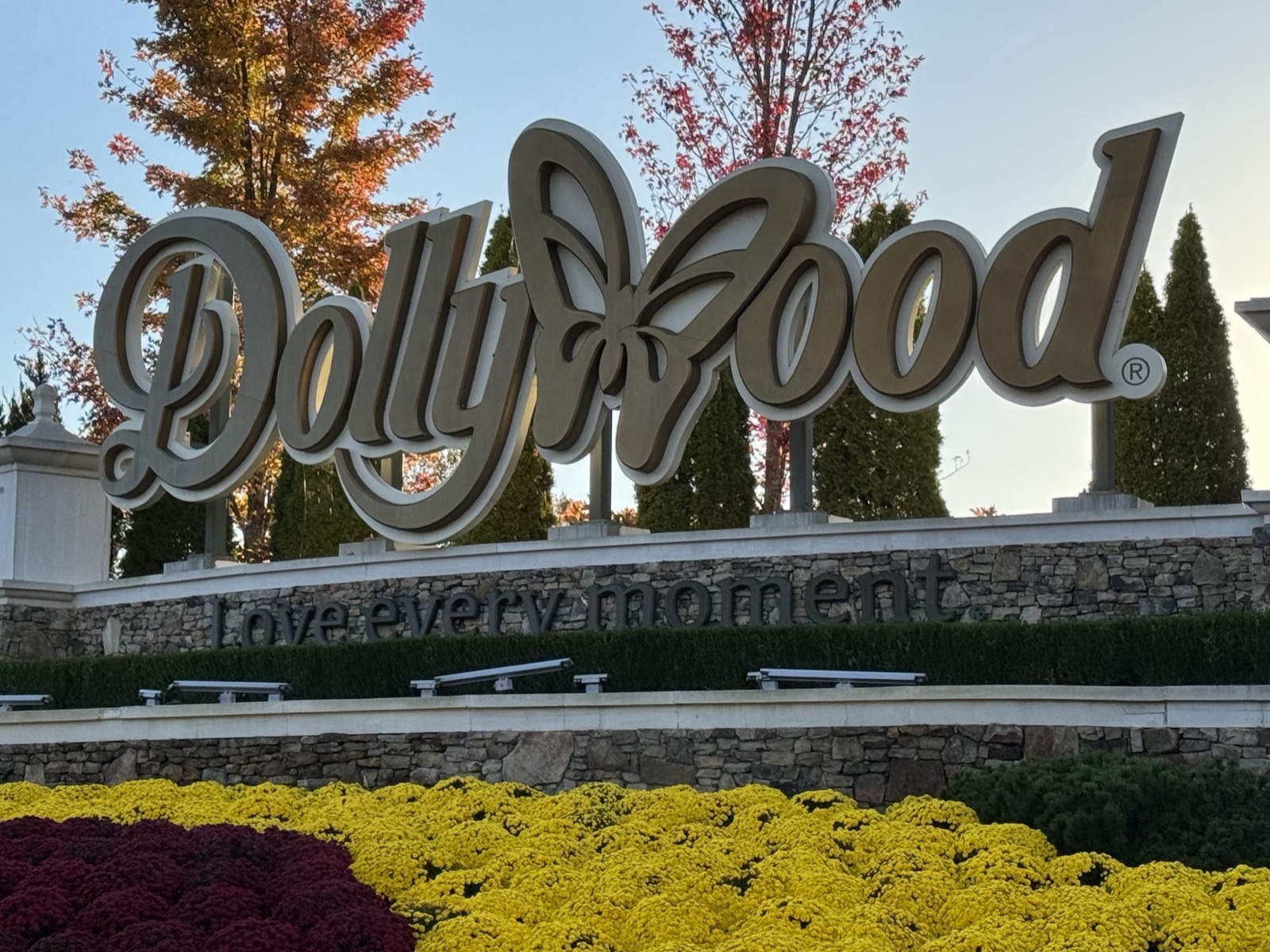 The main sign at Dollywood, Pigeon Forge, Tennessee, 26 October 2023 — the park is owned half by Herschend Family Entertainment and half by Dolly Parton Productions, and Forbes' 2021 estimate put her half at about $165 million