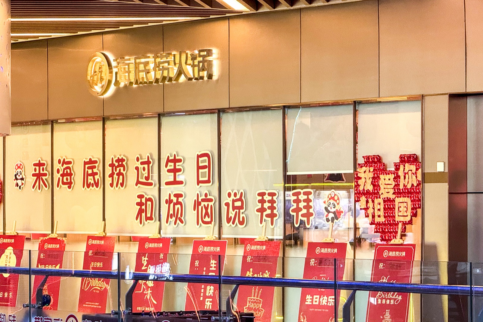 The gilt Haidilao Hotpot sign above a mall-level restaurant at Parkin Mall, Zhengzhou, on 2 October 2024, birthday banners in the windows — one of 1,383 Haidilao restaurants at the end of 2025, almost all of them in mainland China, the fact on which Beijing's Announcement 21 of 2026 turns for the founding family