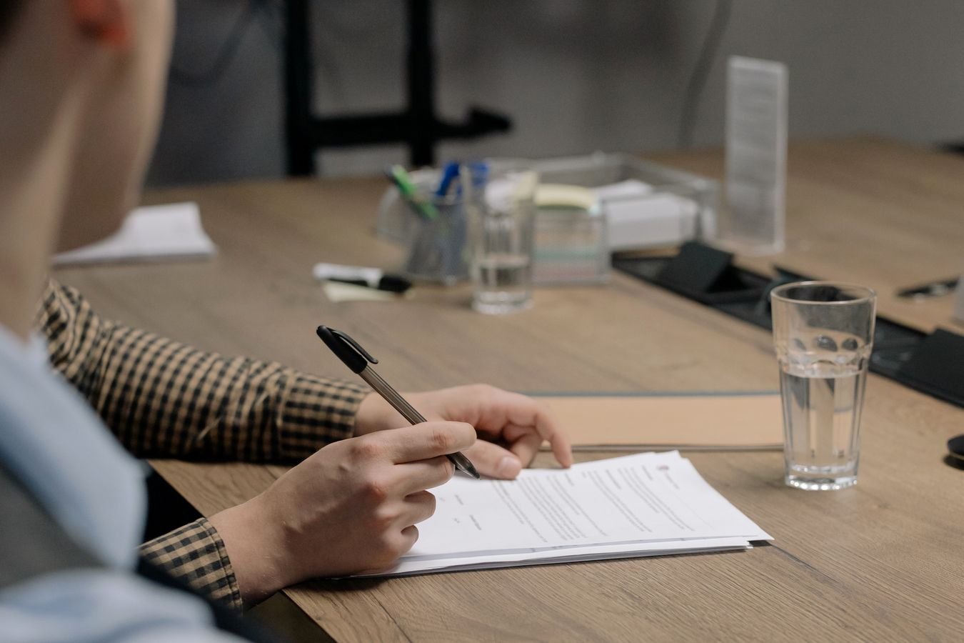 A person signing a document across a boardroom table — the estate-partition agreement is the instrument Korean law lets a family use to override the statutory shares, and the one the Koo heirs have spent three years trying to unwind